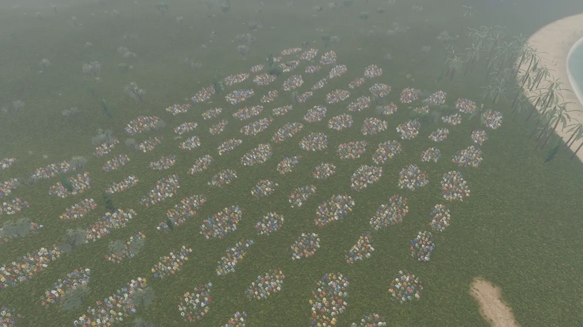 Rows of seated groups on a green field beside the sea, seen from above